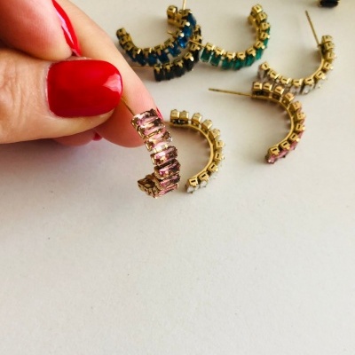 Brincos meia argola com pedras coloridas e base dourada sobre fundo branco