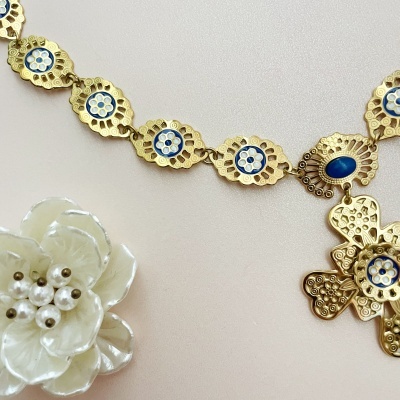 Colar dourado com detalhes azuis e colar de flores de madrepérola branca com contas peroladas