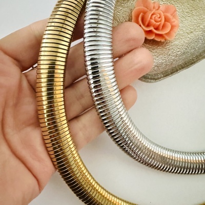 Colares metálicos dourado e prateado com textura estriada na mão junto a flor decorativa
