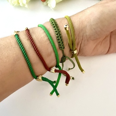 Pulseiras trançadas coloridas com detalhes dourados no pulso