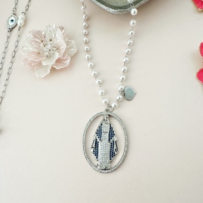 Colar com pendente oval da Nossa Senhora em azul e branco com corrente de pérolas, sobre fundo bege com flor rosa claro