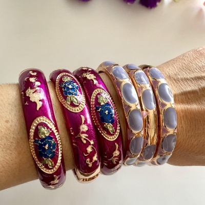 Pulseiras esmaltadas vermelhas com detalhes florais e pulseiras douradas com pedras azuis claras no braço