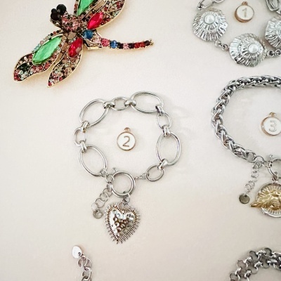 Pulseira prateada com pendente de coração texturizado e etiqueta com número 2