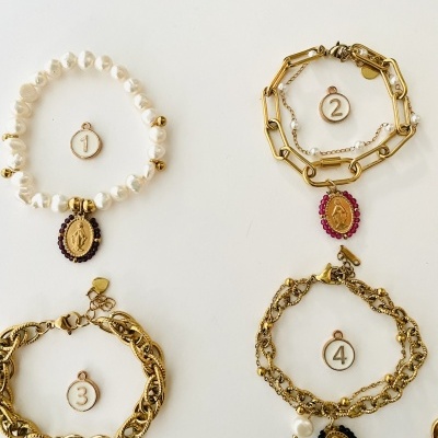 Quatro pulseiras de senhora com medalhas penduradas numeradas de 1 a 4 em fundo branco