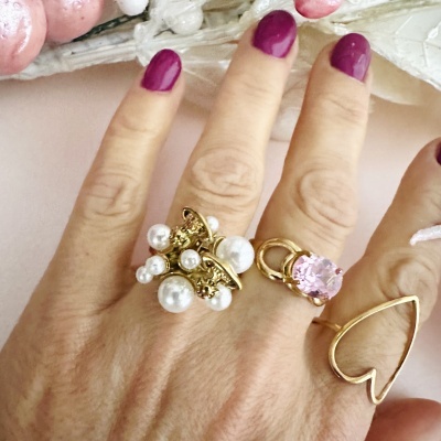 Mão com três anéis dourados e unhas roxas.