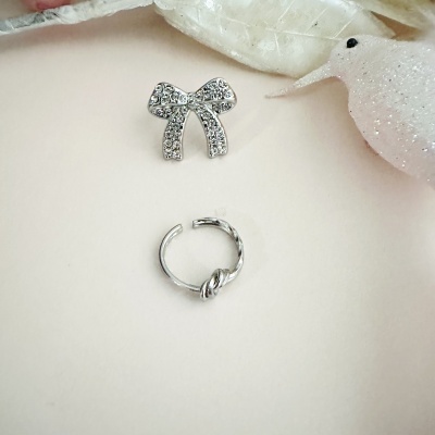 Anel prateado com nó e broche de laço cravejado