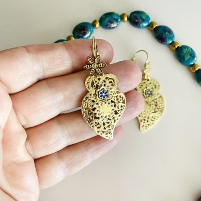 Brincos dourados com padrão floral e colar de contas azuis e douradas