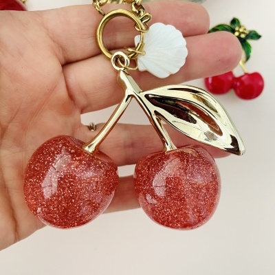 Colar com pendente de duas cerejas vermelhas brilhantes e folha dourada