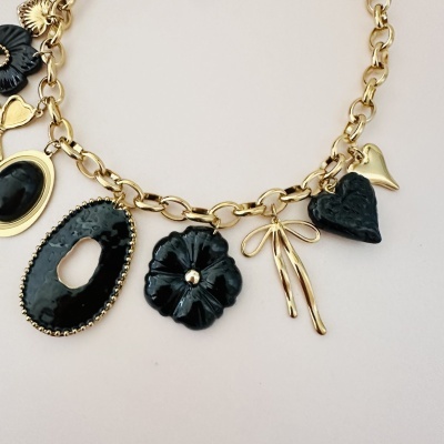 Colar dourado com pendentes pretos e dourados de formas variadas.