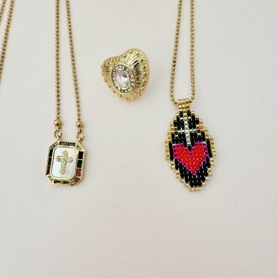 Joalharia com colares dourados e anel com pedra em fundo branco