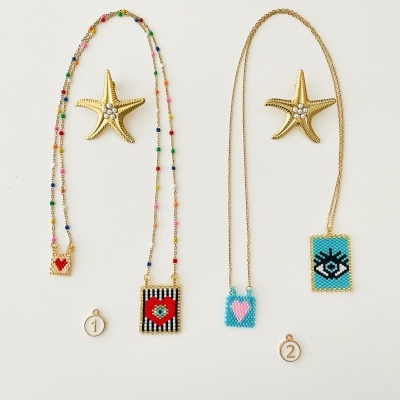 Dois colares coloridos com pendentes retangulares ao lado de estrelas do mar douradas