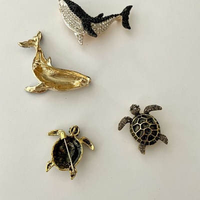 Broches de animais marinhos em metal e pedras em fundo claro