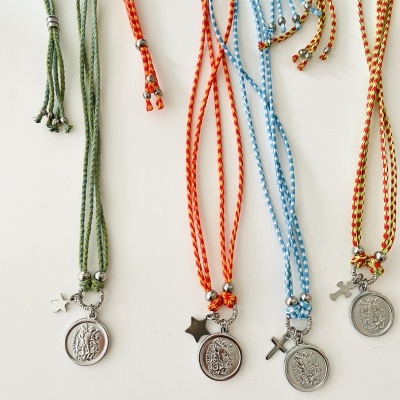 Colares coloridos com medalhas prateadas e pequenos pingentes em cruz e estrela