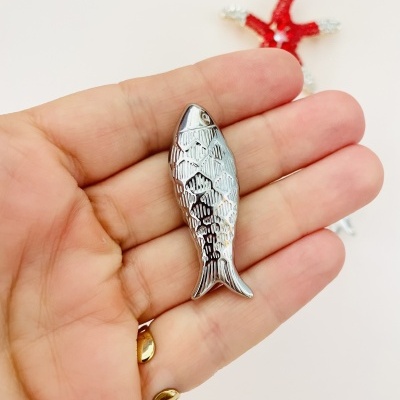 Peça metálica pequena em forma de peixe prateado
