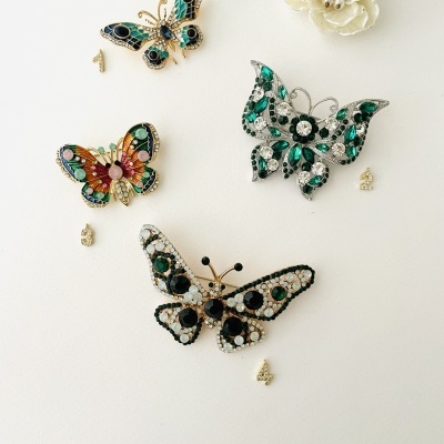 Broches em forma de borboleta com pedras coloridas e adorno floral creme