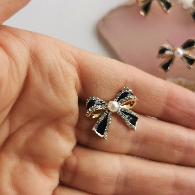 Brinco laço preto com strass e pérola na mão