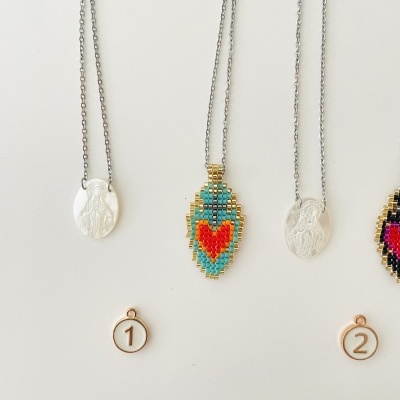 Colares com pendentes metálicos e coloridos pendurados com etiquetas numeradas