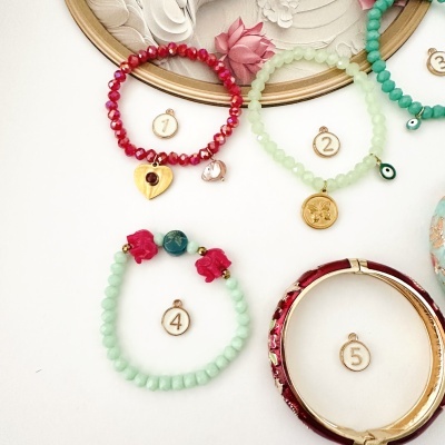 Pulseiras coloridas com contas e amuletos dourados, numeradas com etiquetas 1, 2, 4 e 5