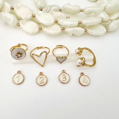 Conjunto de anéis dourados com pérolas e cristais, medalhas numeradas e colar de pérolas brancas