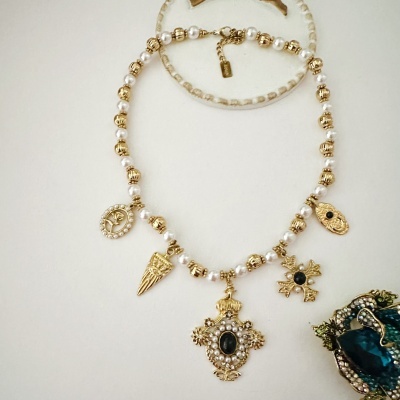 Colar de pérolas brancas e contas douradas com pendentes e etiqueta da marca JUINNE