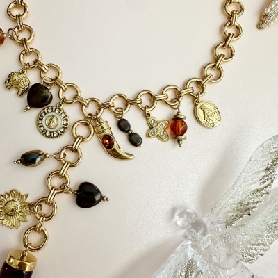 Colar dourado com vários pendentes coloridos e decorativos num fundo claro