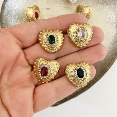 Quatro brincos dourados em forma de coração com pedras coloridas e textura detalhada