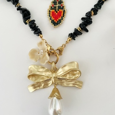 Conjunto de colares com contas pretas, pendente de miçangas coloridas, flor branca e laço dourado com pérola.