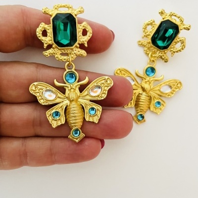 Brincos dourados em forma de inseto com pedras coloridas