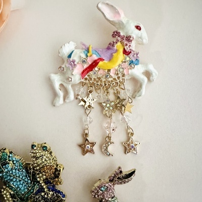 Broche coelho branco com enfeites coloridos e pendentes dourados estrelas e lua