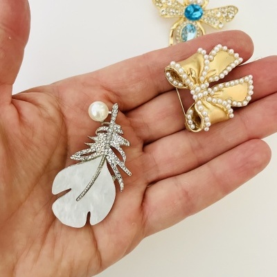 Alfinetes de broche decorativos em mão com fundo branco