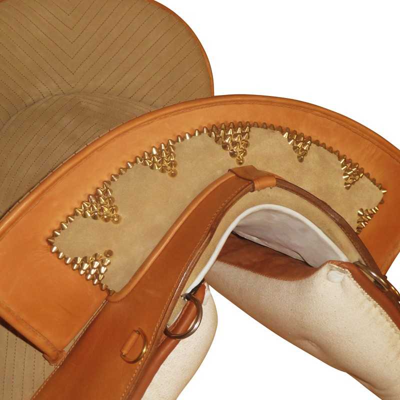 Selim de equitação castanho com tachas douradas e tecido bege.