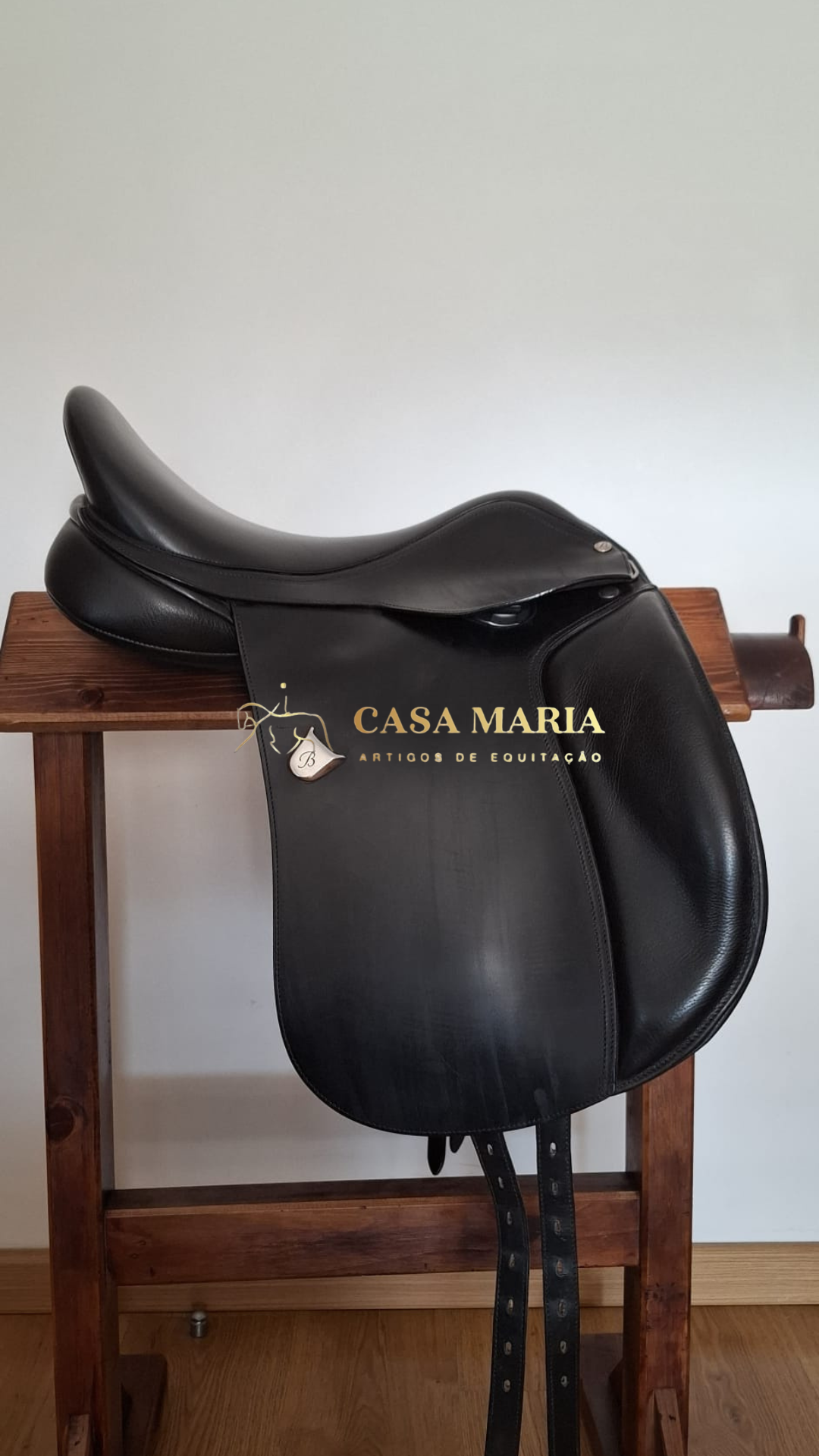Sela de equitação preta em couro sobre bancada de madeira
