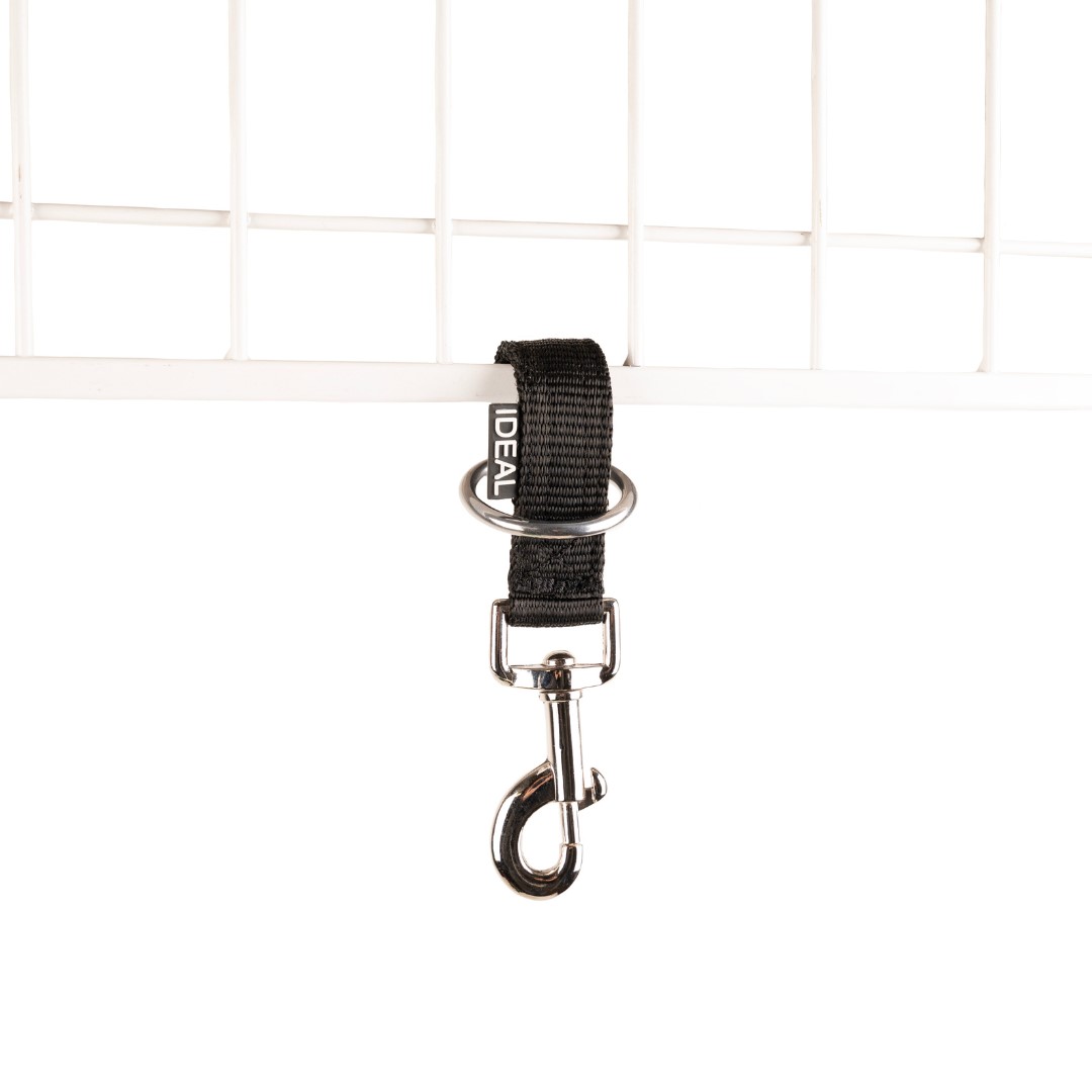 Gancho metálico com fita preta e texto IDEAL pendurado numa estrutura branca de metal