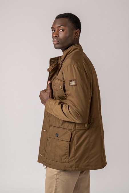 Homem a usar casaco castanho com bolsos e etiqueta no braço esquerdo