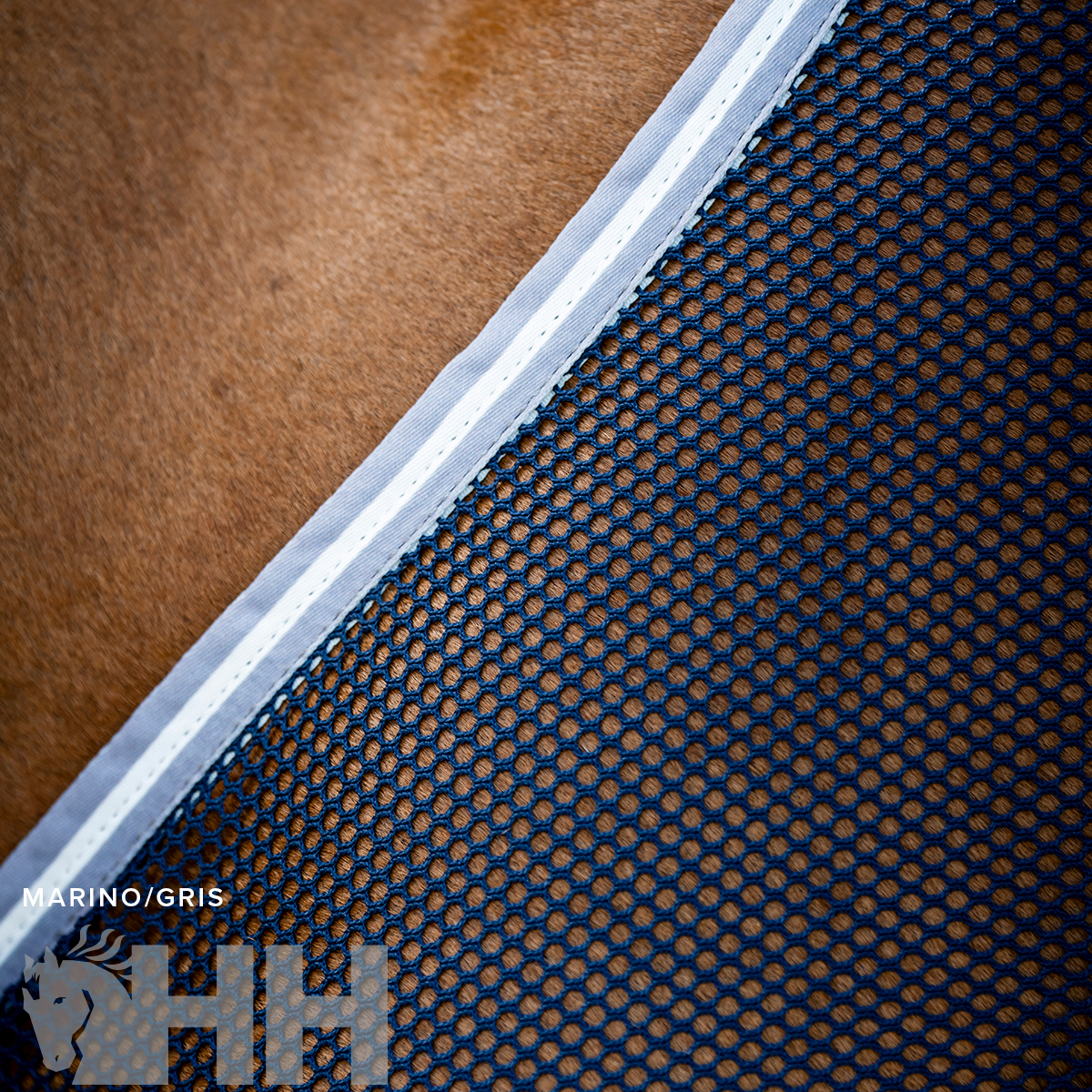 tecido de malha azul escuro com padrão de buracos e borda branca sobre superfície castanha