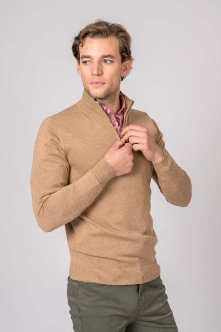 Homem com camisola bege de malha, camisa rosa e calças verdes