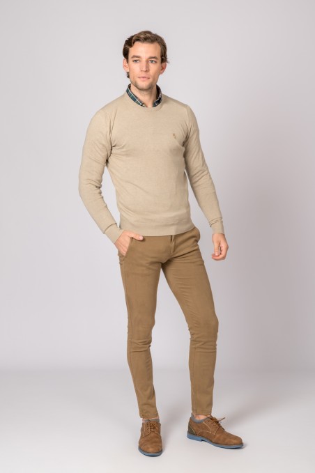 Homem com camisola bege de malha e calças castanhas justas, sapatos castanhos.