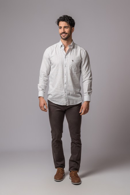 Homem com camisa xadrez clara, calças castanhas e sapatos castanhos, fundo cinza