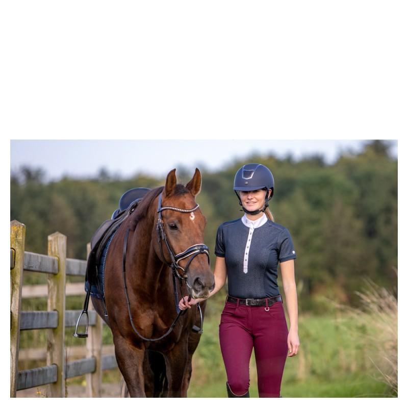 Mulher a conduzir cavalo castanho com arreios pretos em ambiente rural