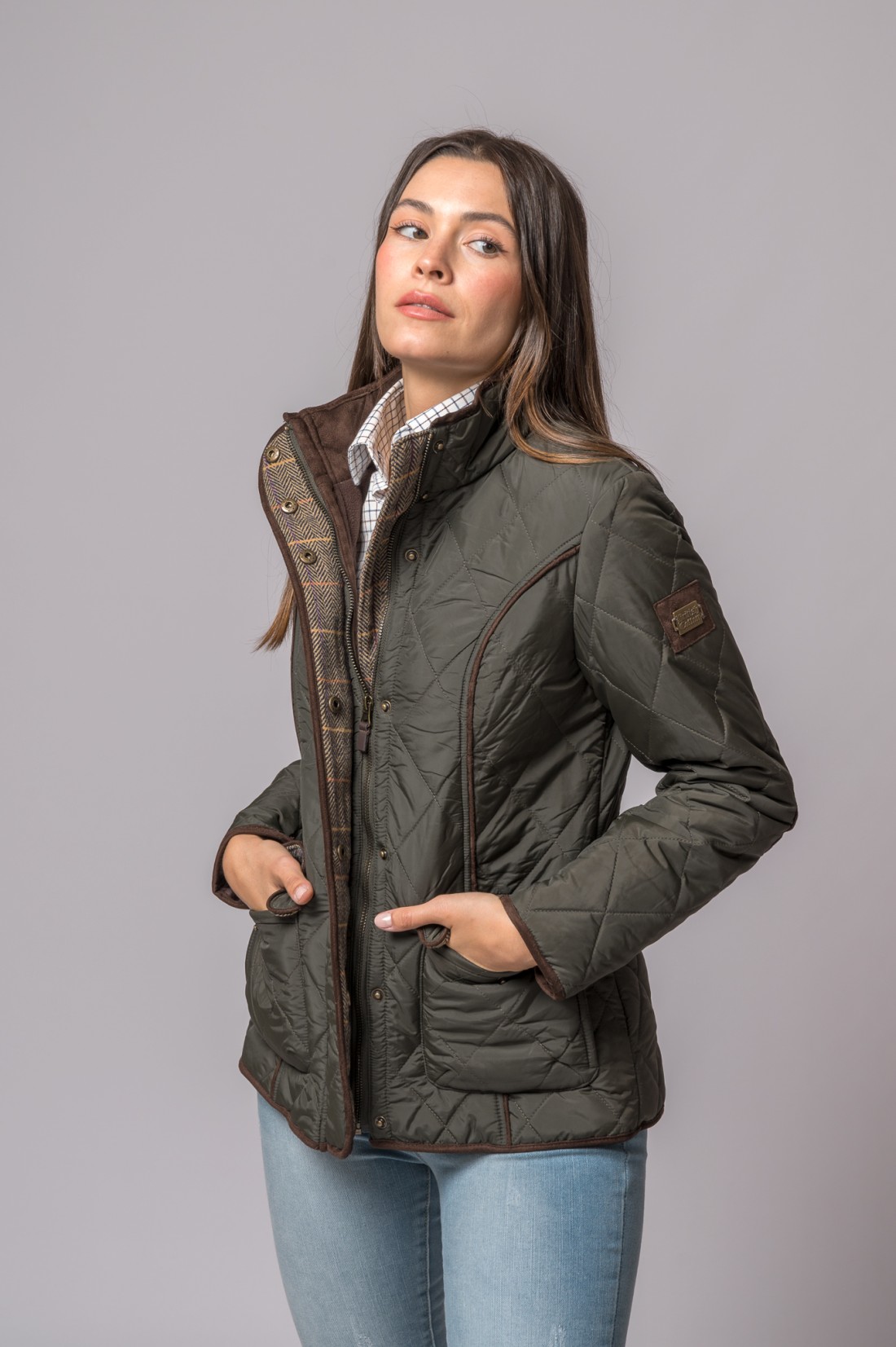 Casaco acolchoado verde-oliva com bolsos e detalhes castanhos em modelo feminina