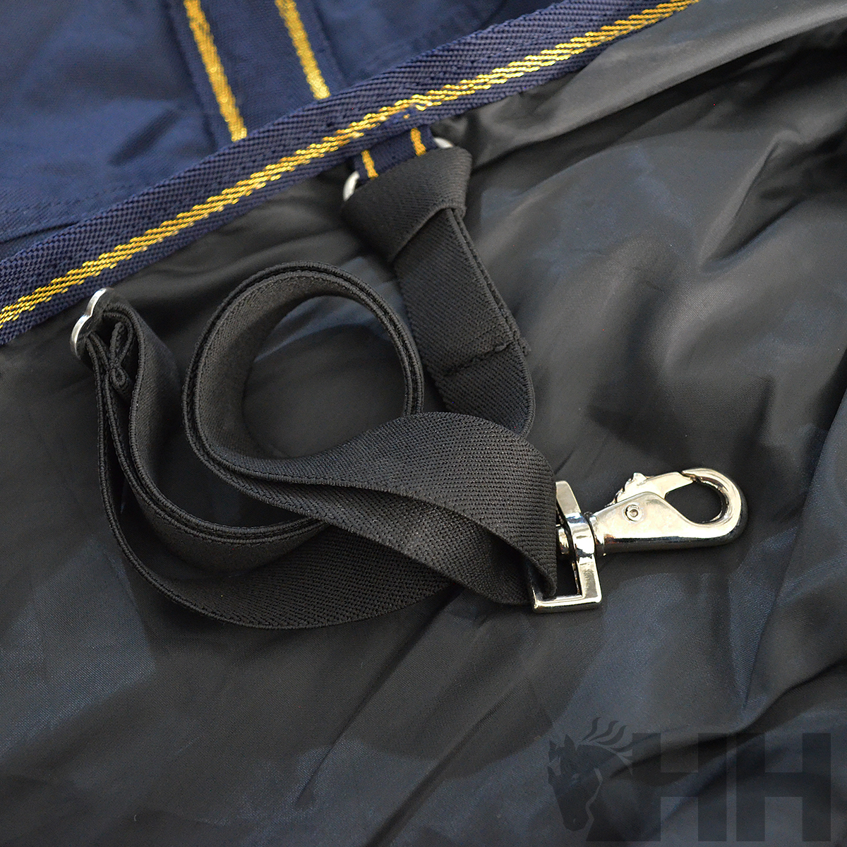 Alça preta com fecho metálico sobre tecido azul e preto