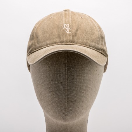 Boné bege com bordado branco BC em manequim de tecido cinzento