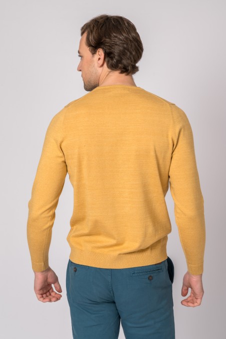 Homem de costas com camisola amarelo mostarda e calças azuis