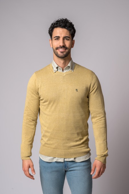 Homem com camisola bege e camisa cinza com calças de ganga