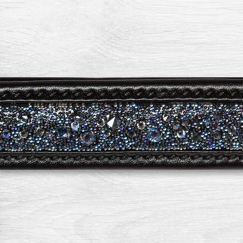 Faixa preta de pele com pedraria azul e transparente em fundo branco texturado