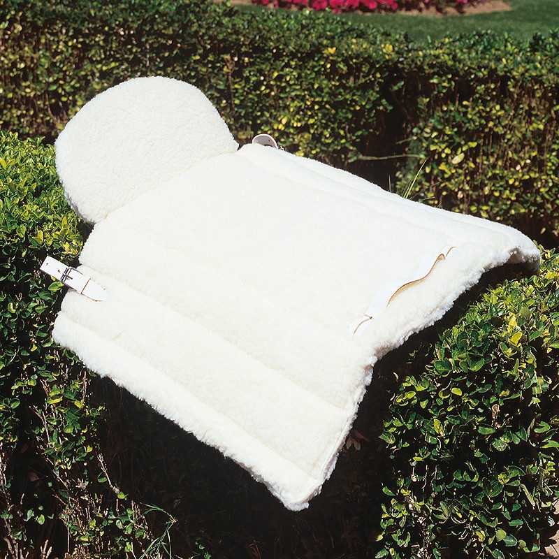 Sela branca felpuda com fivelas destacada sobre arbusto verde.