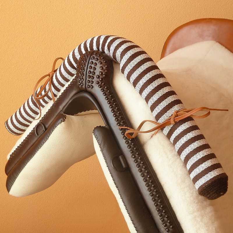 Pantufas castanhas com sola antiderrapante e forro branco felpudo com rolinho anatómico às riscas castanhas e brancas numa cadeira de couro castanho.