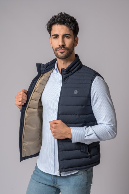 Colete masculino azul escuro acolchoado com camisa azul clara e jeans azuis