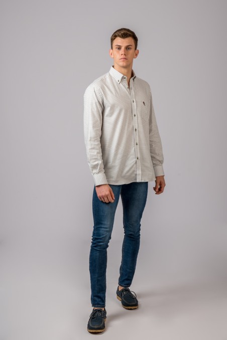 Homem com camisa branca de padrão de linhas finas, jeans azuis e sapatos azul escuro em fundo cinzento