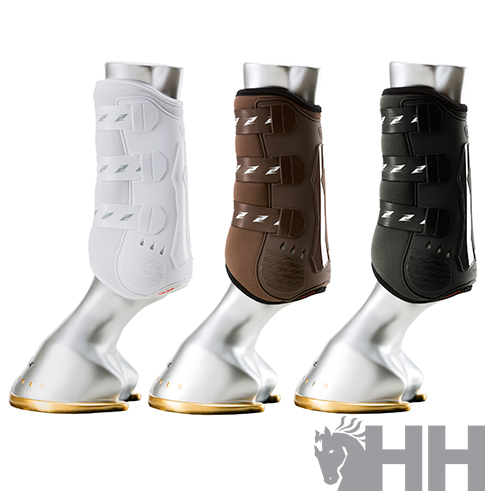 Três botas de proteção equestres em branco, castanho e preto com tiras em velcro, mostradas em pés metálicos com ferraduras douradas.